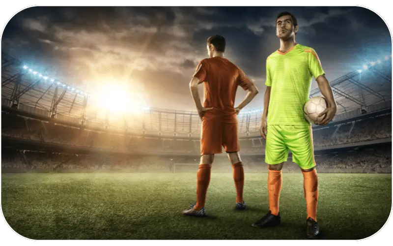 Two footballers standing on a floodlit pitch